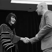 President and student shake hands